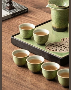 Detail of green kiln-fired ceramic tea set with ice-crackle glaze on a wooden table