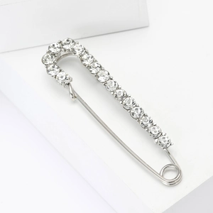 Silver safety pin brooch with sparkling crystals on white surface for women's coats