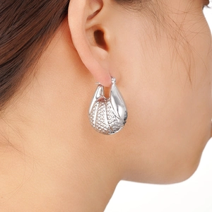 Gros plan de boucles d'oreilles argentées en forme de coquillage au style marin