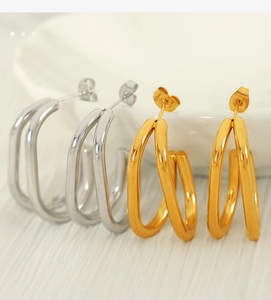 Close-up of gold and silver chunky U-shaped geometric earrings in polished metal