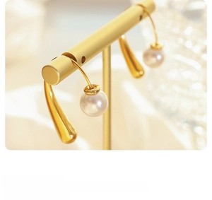 Detailed macro view of French style gold-plated earrings with pearls on a stand