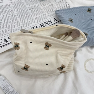 Detailed view of bear embroidery on corduroy cosmetic bags in cream and blue