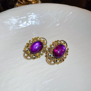 Macro shot of French vintage purple oval gemstone earrings with pearls in a ceramic tray