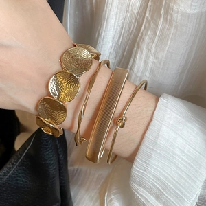 Detail of four-piece gold irregular bracelets with hammered textures and twisted designs
