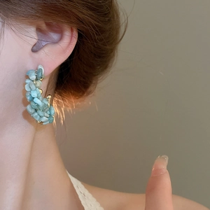 Macro shot of light blue natural stone beads and gold accents on C-shaped hoop earrings