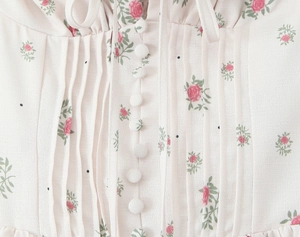 Detail of floral print fabric featuring fabric-covered buttons and ruffled lace trim
