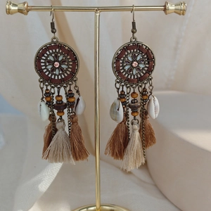 Close-up of Bohemian long tassel earrings with wood beads, shells, and metal discs