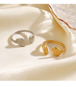 Dettaglio di anelli a forma di ala in oro e argento su elegante seta color champagne