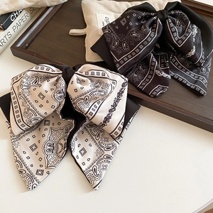Detail showing paisley satin bow clips in black and beige on vintage background