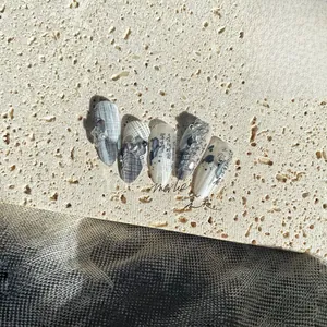 Close-up of ink-style press-on nails with silver foil, pearls and 3D gemstones