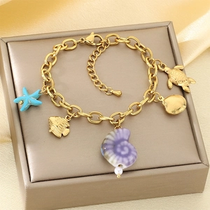 Bracelet doré avec pendentifs étoile de mer, poisson et tortue sur fond de satin champagne