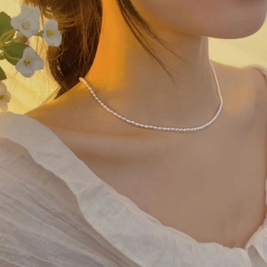 Close-up of minimalist natural freshwater pearl necklace on model with 14K gold clasp