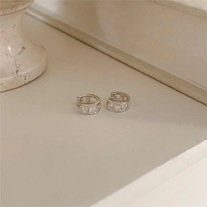 Detailed view of silver huggie earrings with pavé square zirconia on elegant background