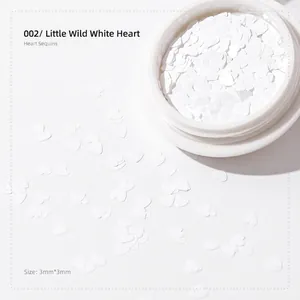 Close-up of 3mm white heart-shaped nail art sequins in a round container for manicures