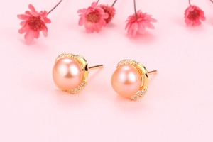 Macro shot of orange-pink freshwater pearl earrings with gold crown cubic zirconia settings