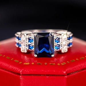 Close-up of a luxury square blue gemstone ring with four-prong setting and side diamonds