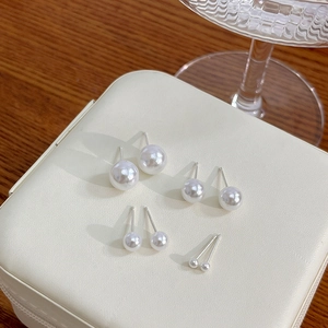 Elegant white pearl stud earrings set with silver needles on luxury jewelry box