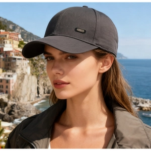 Close-up of dark grey baseball cap with metal SPORT badge on textured fabric in the sun