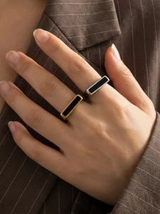 Close-up of minimalist black enamel rectangular rings in gold and silver finish