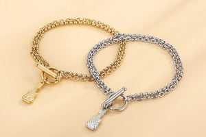 Detail von gold- und silbernen Gitarrenarmbändern mit OT-Verschluss auf beigem Grund