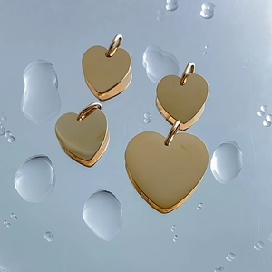 Polished gold stainless steel heart charms in various sizes on water drop background