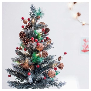 Detailed view of desktop Christmas tree with red berries, pine cones and warm LED lights