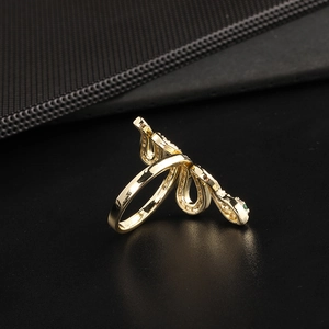 Macro detail of a gold snake ring featuring green gemstone eyes and white cubic zirconia