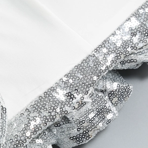 Close-up of sparkling silver sequins and delicate fabric detail on a white cocktail dress
