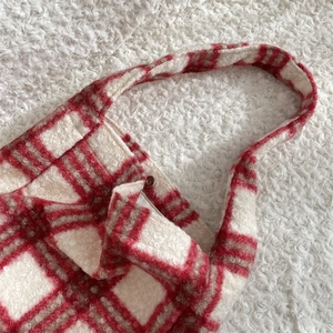 Detail of red and white plaid wool tote bag showing texture and button closure