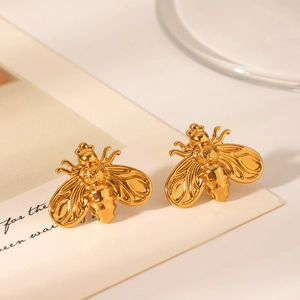 Macro view of gold bee-shaped stud earrings with polished 18K finish on art card