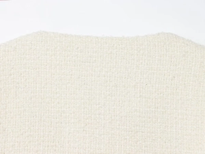 Vue macro montrant le tissage complexe du tissu en tweed bouclé blanc et ses fibres
