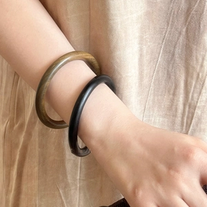 Gros plan de bracelets en bois noir et brun olive avec grain naturel sur le poignet d'un mannequin