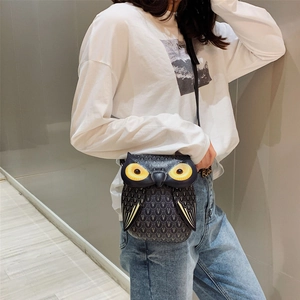 Detailed view of an owl-shaped crossbody bag featuring yellow eyes and textured print