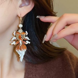 Detail of goldfish earring with white pearl and orange enamel on model's ear