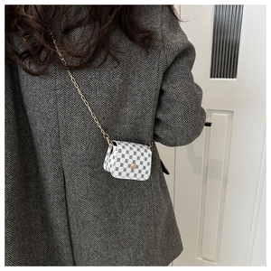 Close-up of white mini crossbody bag with black pattern and golden chain strap