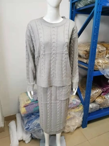 Detail of grey cable-knit sweater and skirt set on mannequin in warehouse