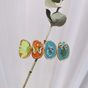 Detail of handmade resin hair clips with dried flowers and gold butterfly charms