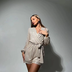 Detail of champagne sequin romper showing V-neckline, long sleeves and belted waistline