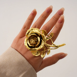 Gros plan d'une grande bague rose dorée avec des pétales réalistes et détails métalliques