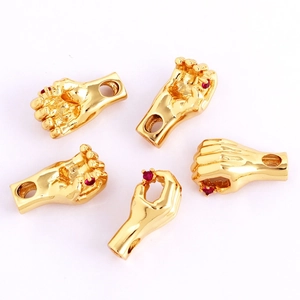 Macro shot of five gold-plated hollow hand charms with red zircon inlay for DIY jewelry