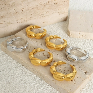 French style wide gold and silver croissant rings set on beige stone background