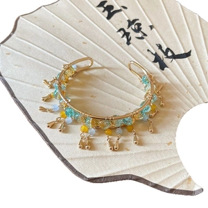 Ethnic style gold tassel bangle with blue beads and vintage metallic charms on a fan