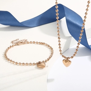 Détail d'une parure de bijoux en billes d'or rose avec pendentifs cœur 3D