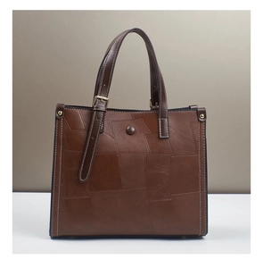 Detail of vintage tote bag showing brown leather texture and gold metal buckle hardware
