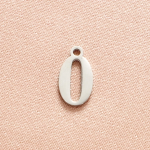 Macro shot of silver number 0 pendant in stainless steel on textured pink fabric