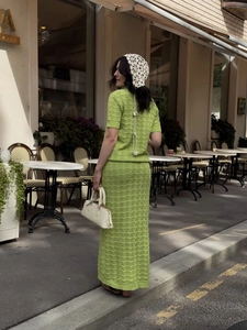 Detail of green hollow-knit polo top and wave-textured skirt in an outdoor cafe setting
