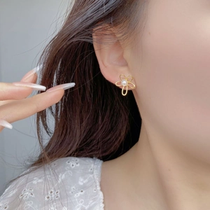 Close-up of vintage flower pearl stud earrings in gold finish on female ear