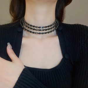 Detailed view of triple-layered black beaded choker necklace on model's neck