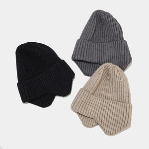 Detailed knit texture of winter ear flap beanies in black, dark grey, and beige