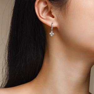 Macro view of 925 silver clover earrings with sparkling moissanite stones on model